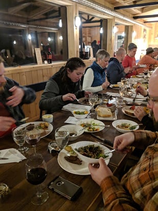 A group of people feasting beneath the northern lights at Dan's Diner in Churchill, Canada.