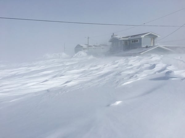 A photo of snow drifts extending to the roof of several houses