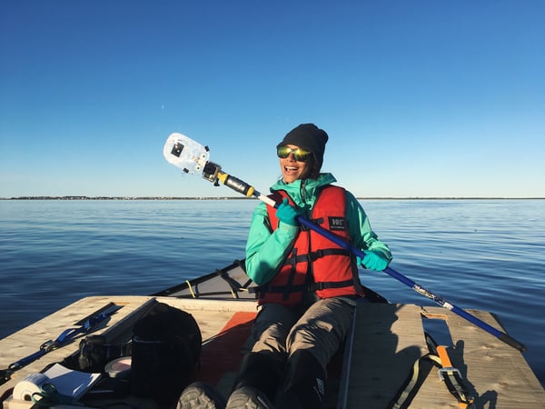 Justine on a boat on the Churchill River holding a device used in her studies.