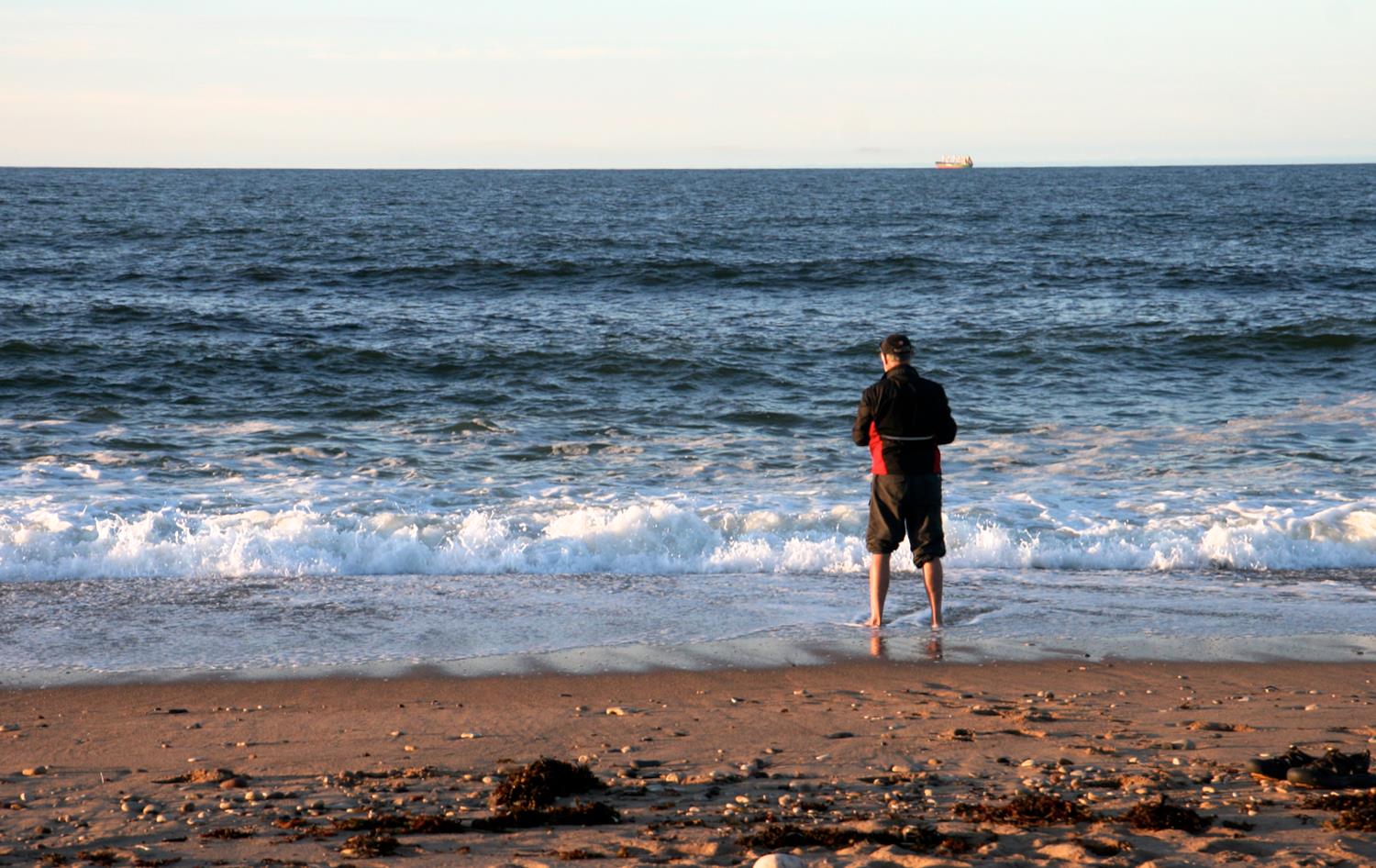 A man stands in the surf on the beach in Churchill Manitoba