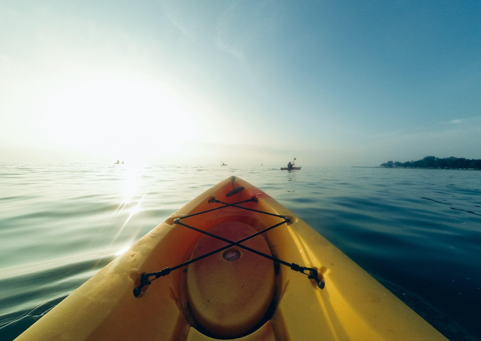 An image taken from the bow of a kayak on calm water in bright sunlight.